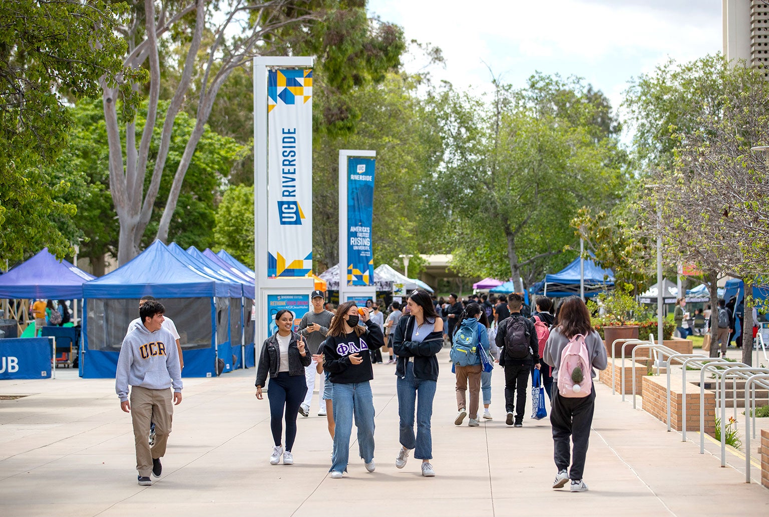 Students walk the campus as booths are set up on Wednesday, April 20, 2022, at UCR.